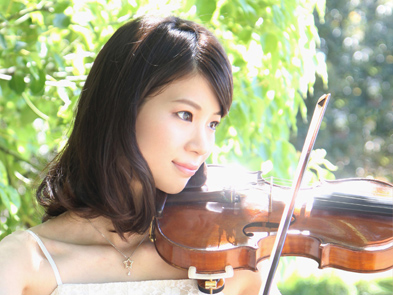 自然な緑の中でバイオリンを弾く女性